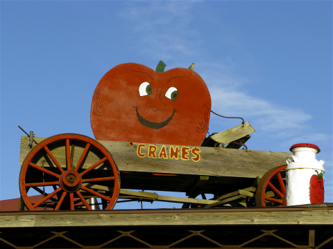 Wooden wagon with red wheels and a red apple sign outside Crane's Pie Pantry in Fennville, Michigan