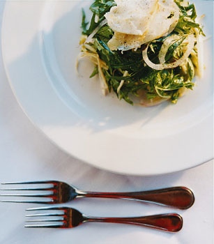 A winter salad on a white plate and white tablecloth with forks