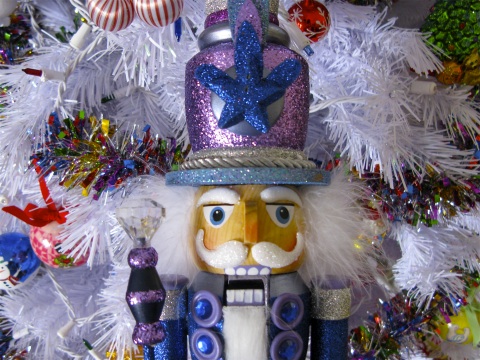 Nutcracker in front of white tree with ornaments