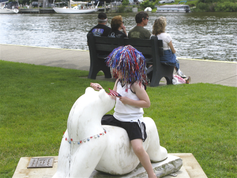 child wearing red white and blue tinsel in her hair along the Black River in South Haven Michigan