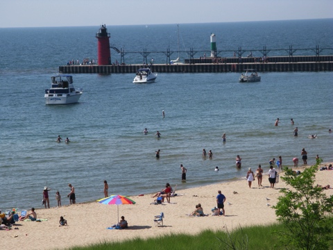South Beach with bathers and pier with lighthouse in South Haven, Michigan