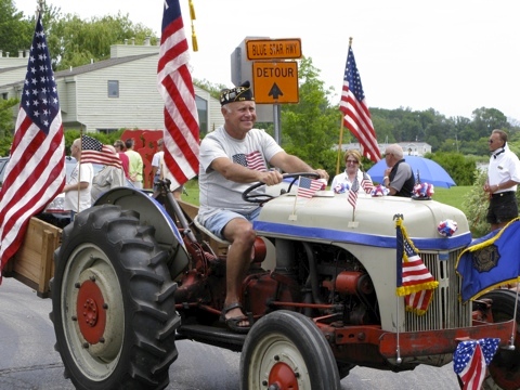 Tractor festooned with flags in the 4th of July parade in Saugatuck, Michigan