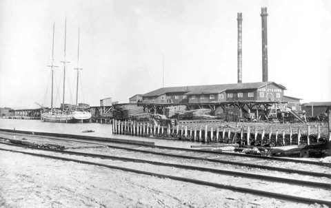 Photo of a Hackley and Hume lumber mill with a schooner at the dock.